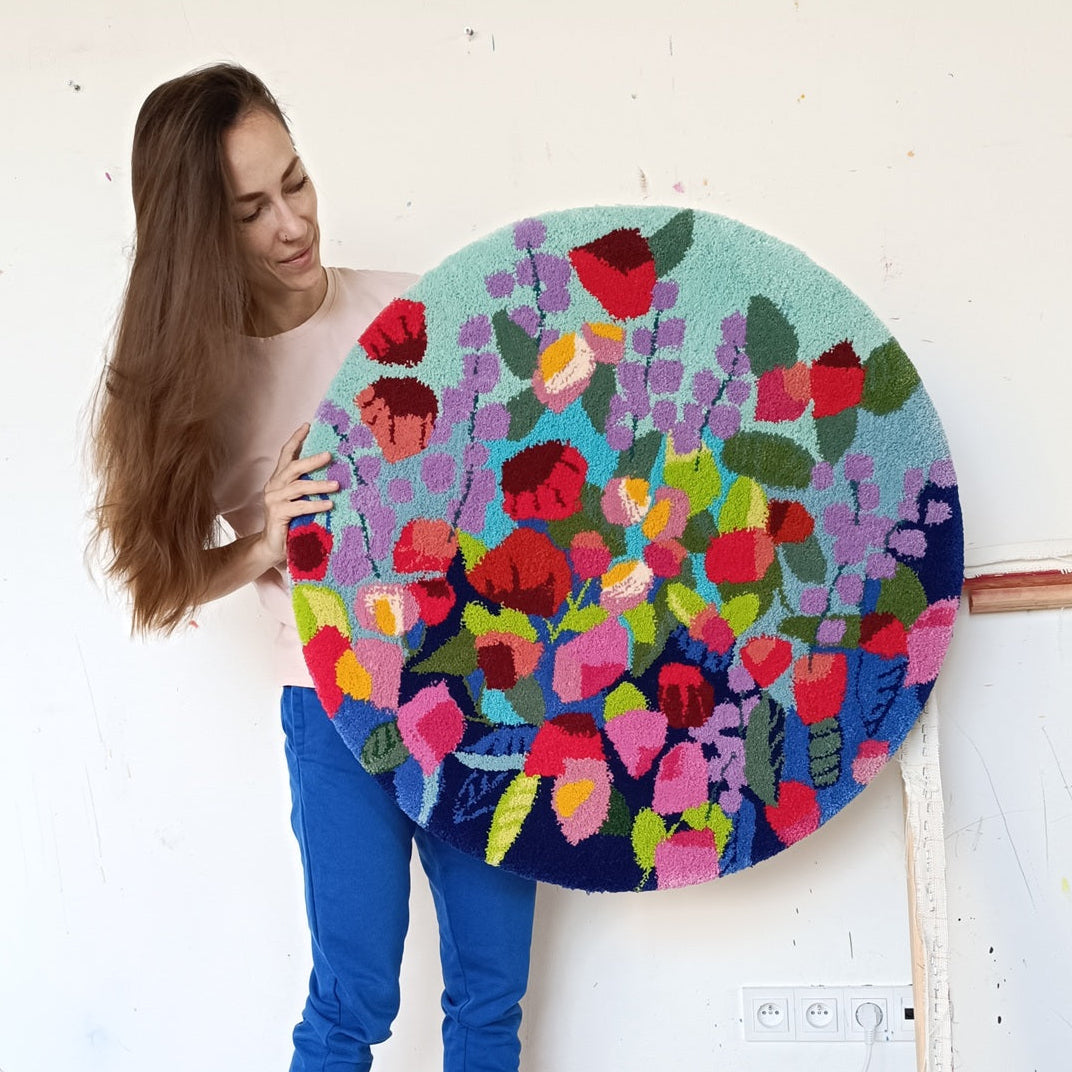 Person holding a colorful circular artwork with floral patterns in a room.