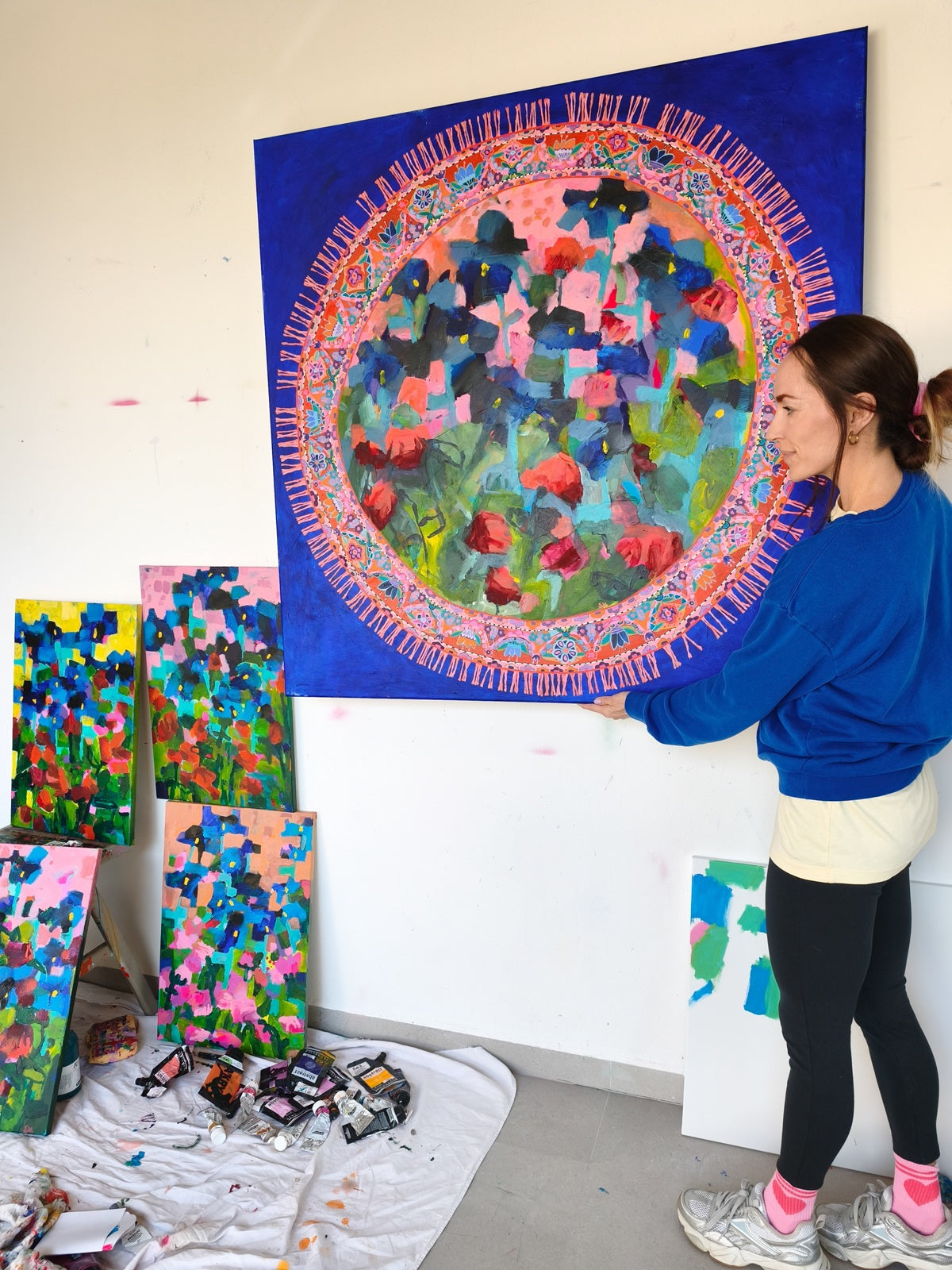 Artist Simona Vojteskova holding Blooming Rug abstract floral painting in her studio